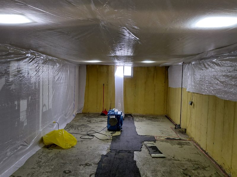 Basement sealed floor to ceiling with polyethylene containment and an air mover running