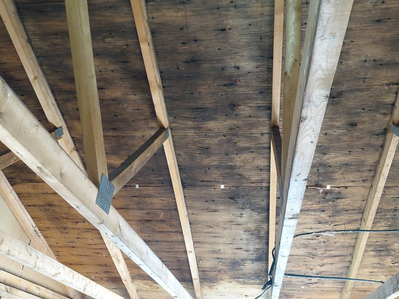 Dark mold staining across plank roof sheathing in an attic before remediation